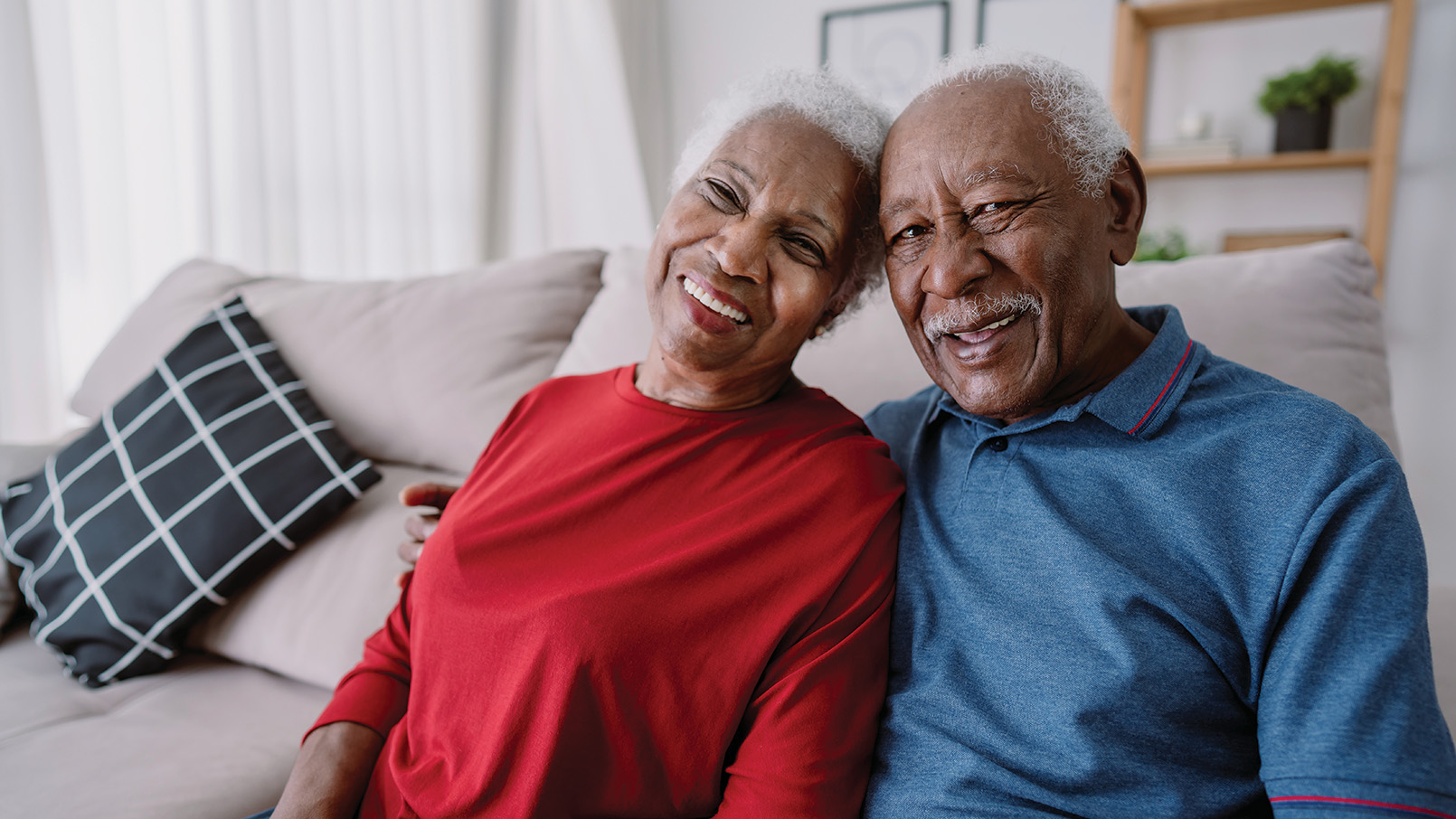 Smiling older Black couple sitting together in a cozy living room.
