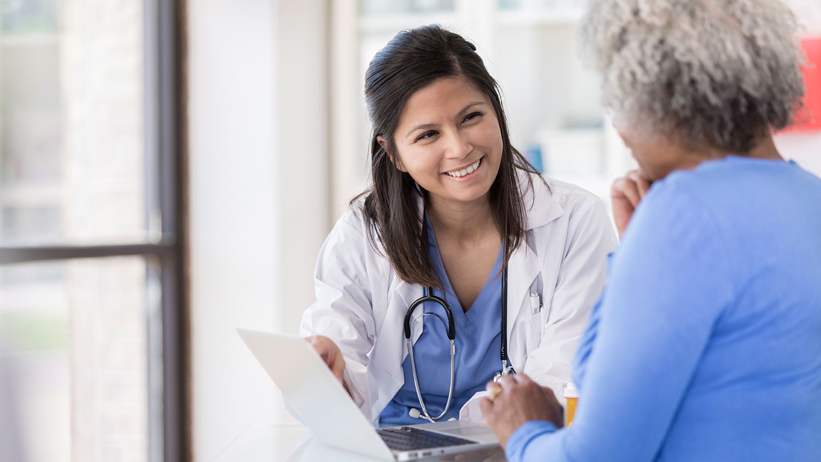 Female doctor talking with an older patient in a clinical setting.